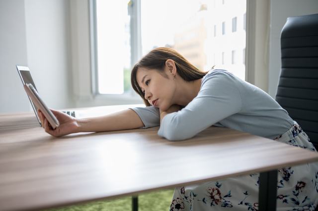 億劫そうにスマホを触る女性